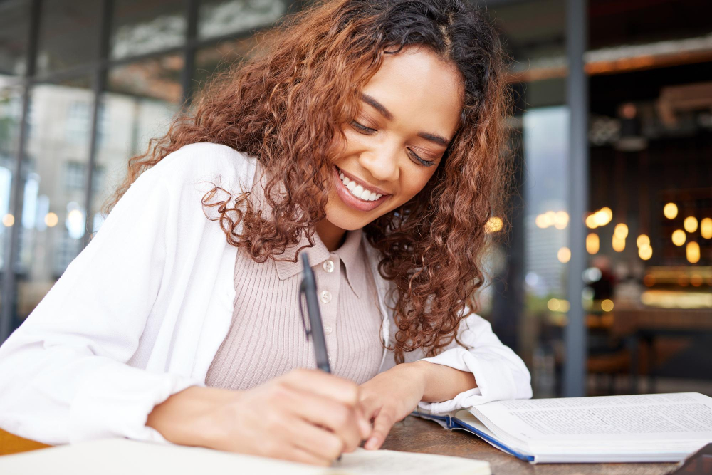 Person smiling with a notebook and pen, representing focus and potential